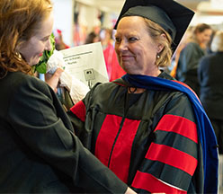 female phd grad in cap and gown with daughter
