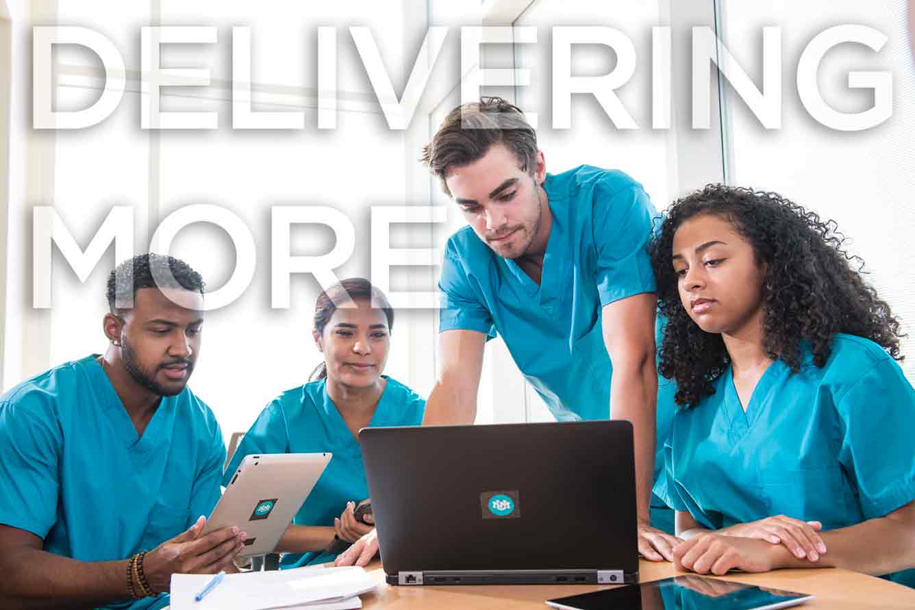 four doctors stand around a laptop and take notes