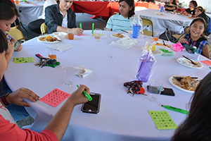 Alunos jogando bingo em volta de uma mesa.