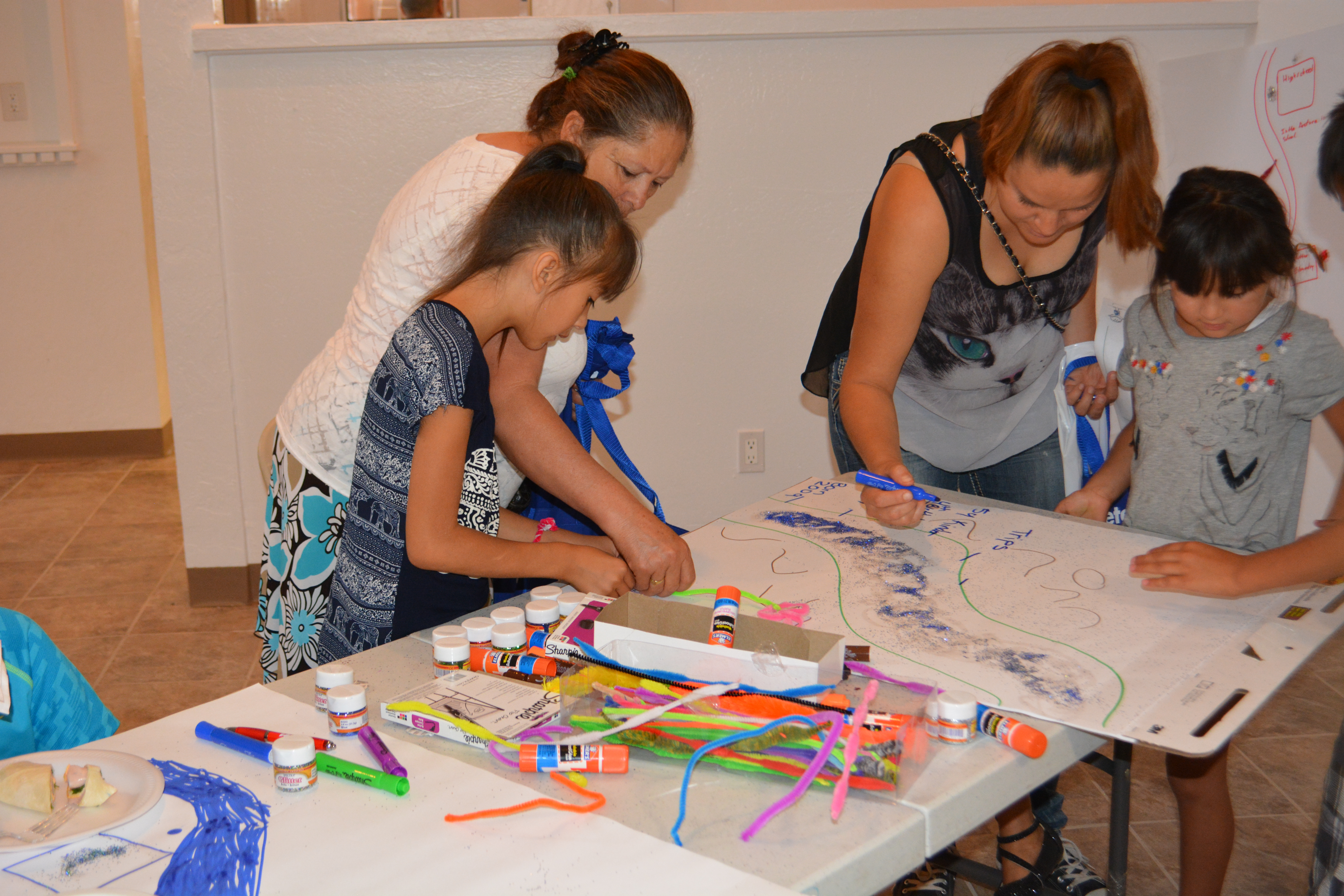 Взрослые помогают детям украшать плакаты "Река жизни".