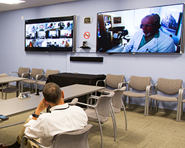 A man sits in front of two screens with teleECHO in session,