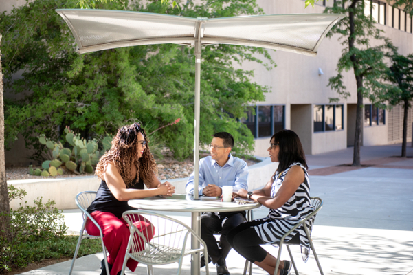 Tres personas disfrutando de una conversación y un almuerzo al aire libre.