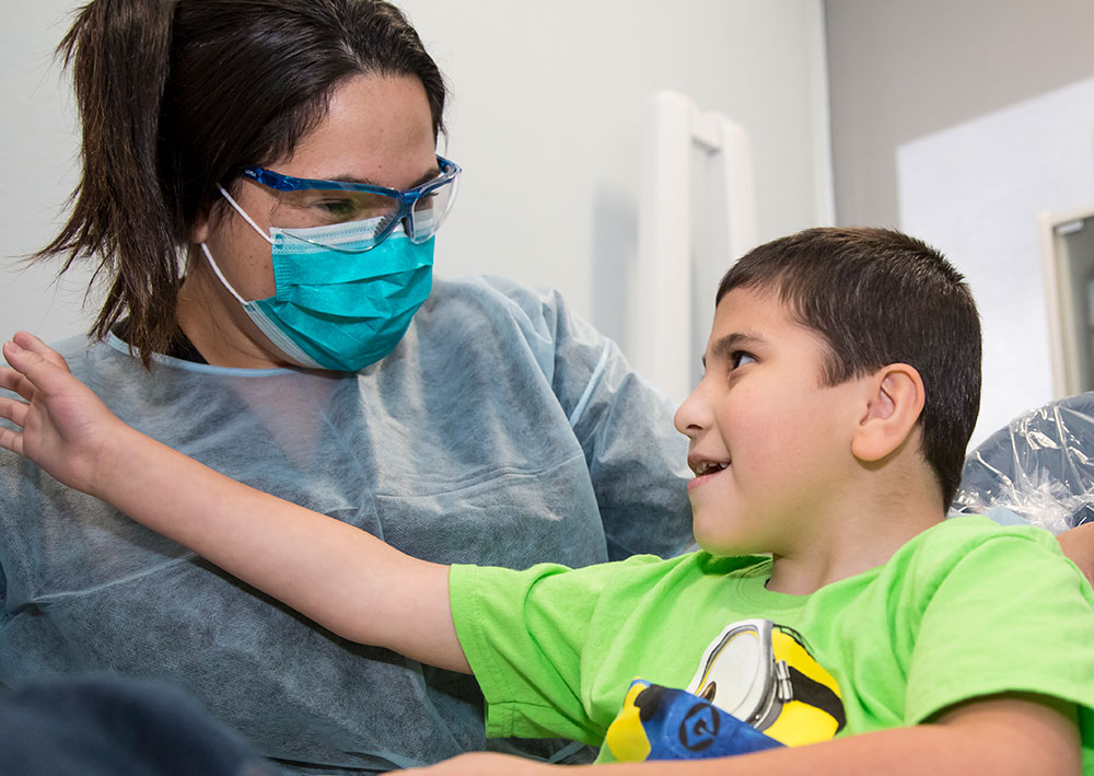 Student der Zahnhygiene interagiert mit kleinem Kind