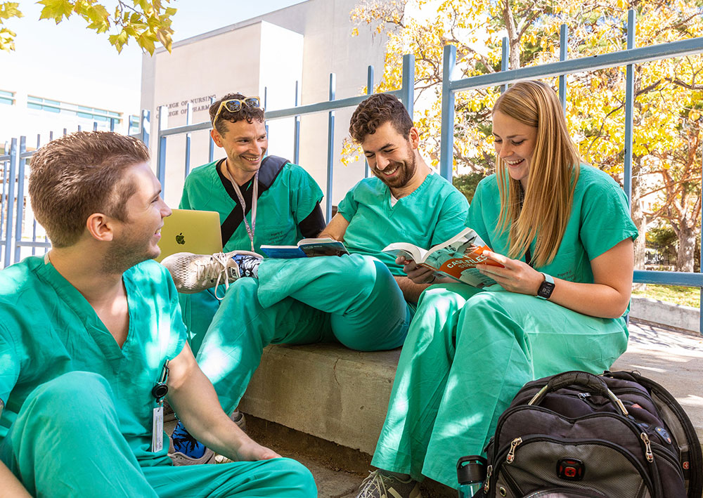 group of students in scrubs lounging outside