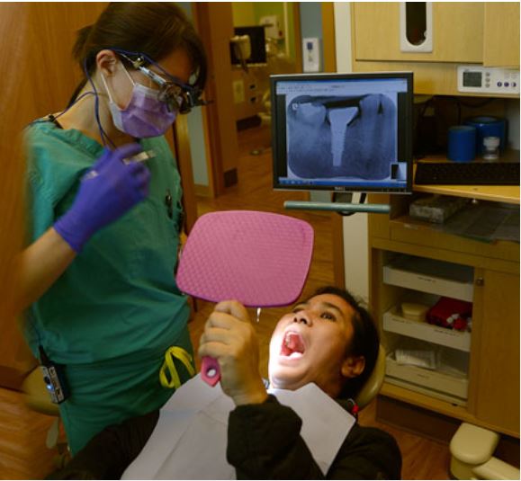 Patient regardant sa bouche dans un miroir à main après la procédure.