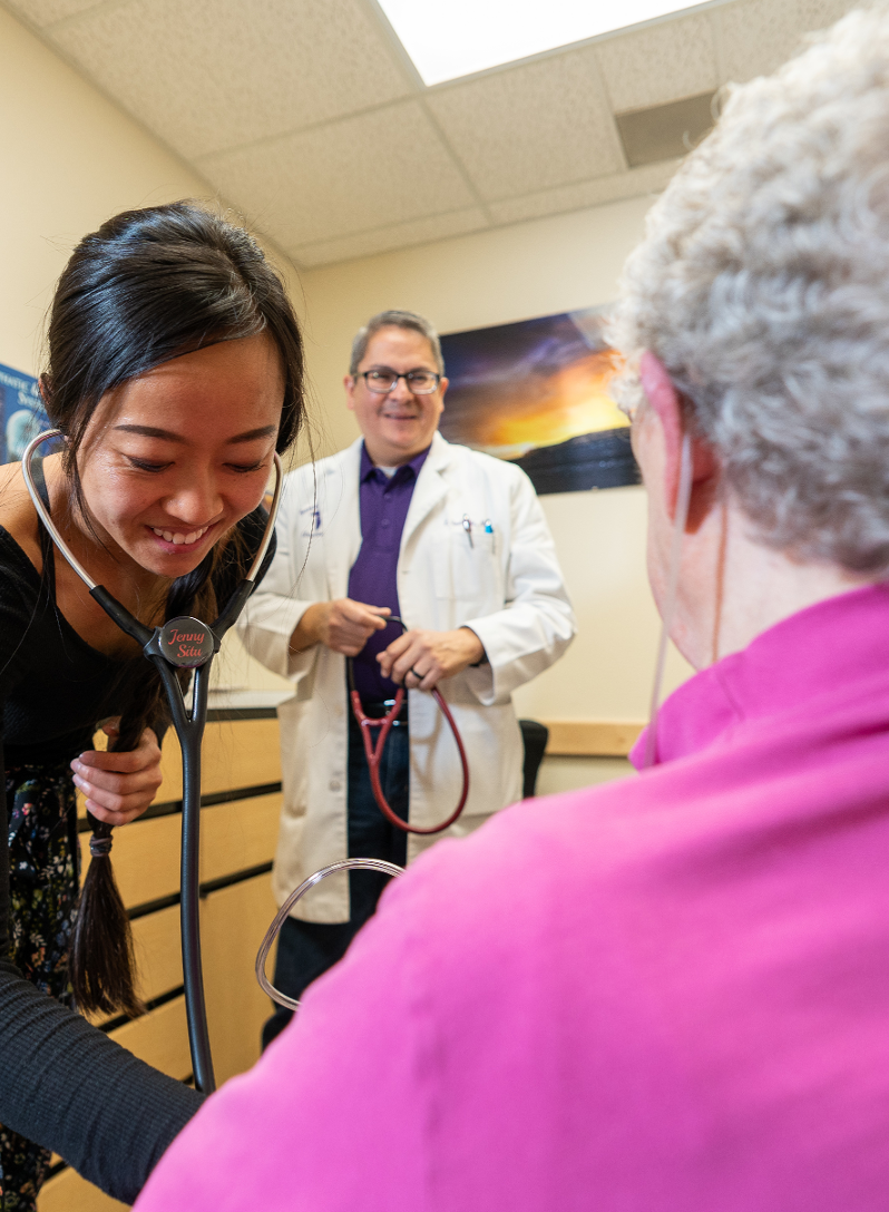 student and preceptor examine senior patient