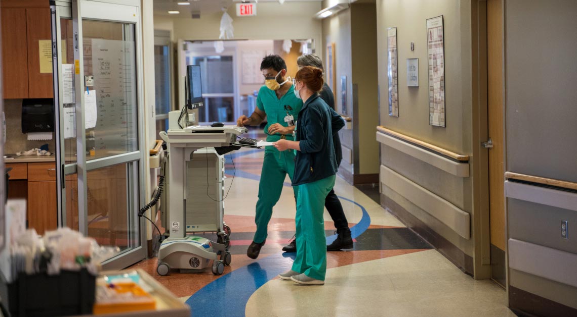 Two staff members standing in Neuro ICU hallway.