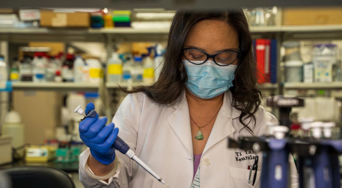 Yi Yang using pipette in lab.