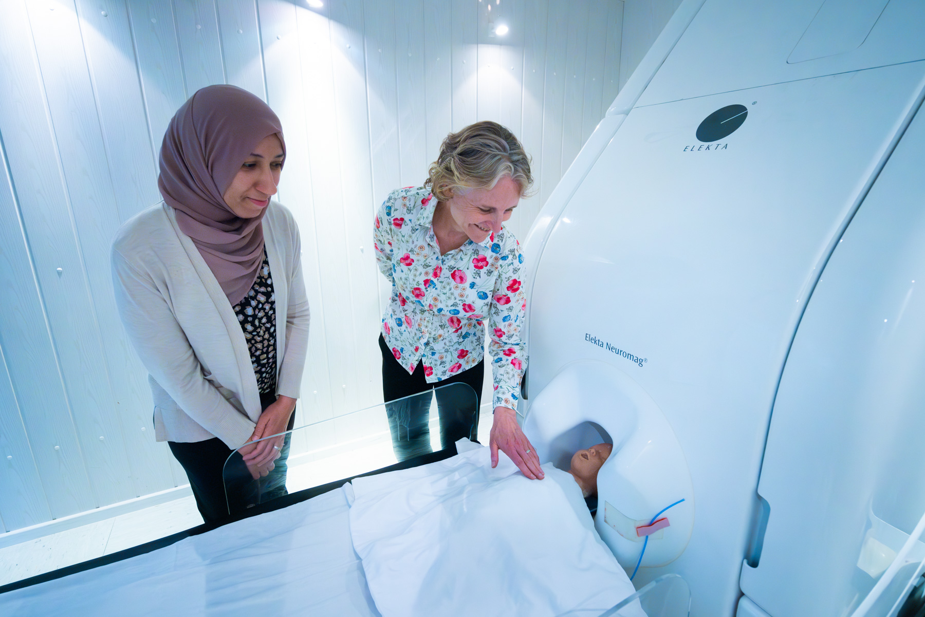 two doctors pose next to a brain scan machine