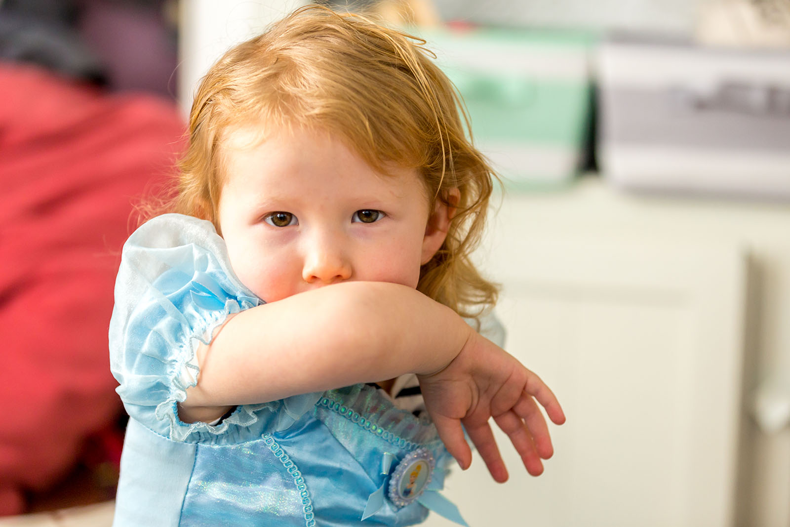 A young child coughing into their arm