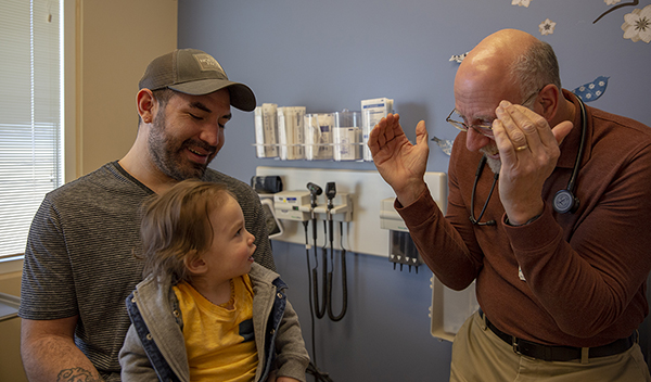 Ein Kinderarzt im Gespräch mit einem Vater und seinem Sohn
