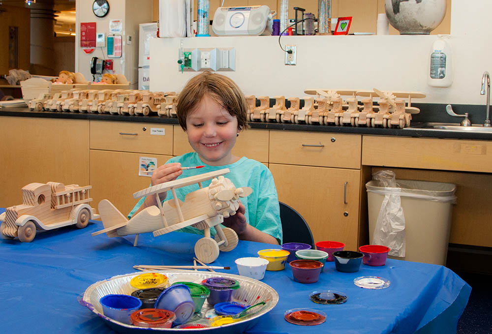 A child painting a wooden toy