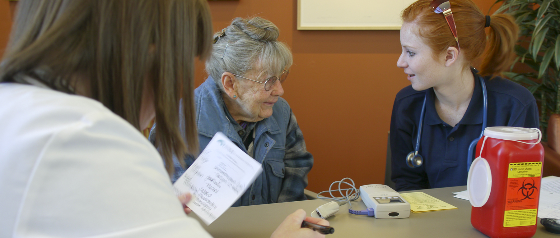 Uma mulher idosa conversando com enfermeiras