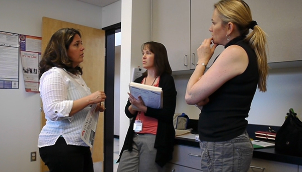 Três mulheres trabalhadoras de saúde conversando