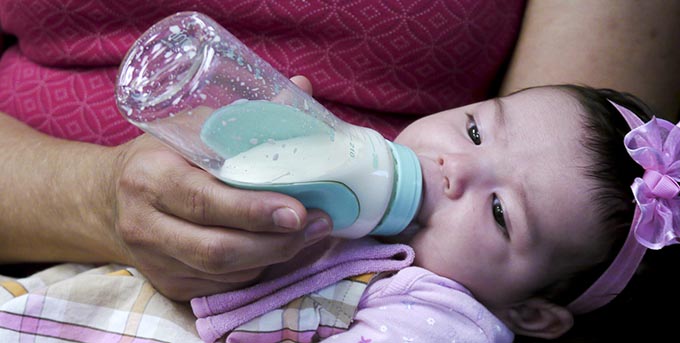 Um bebê bebendo de uma garrafa