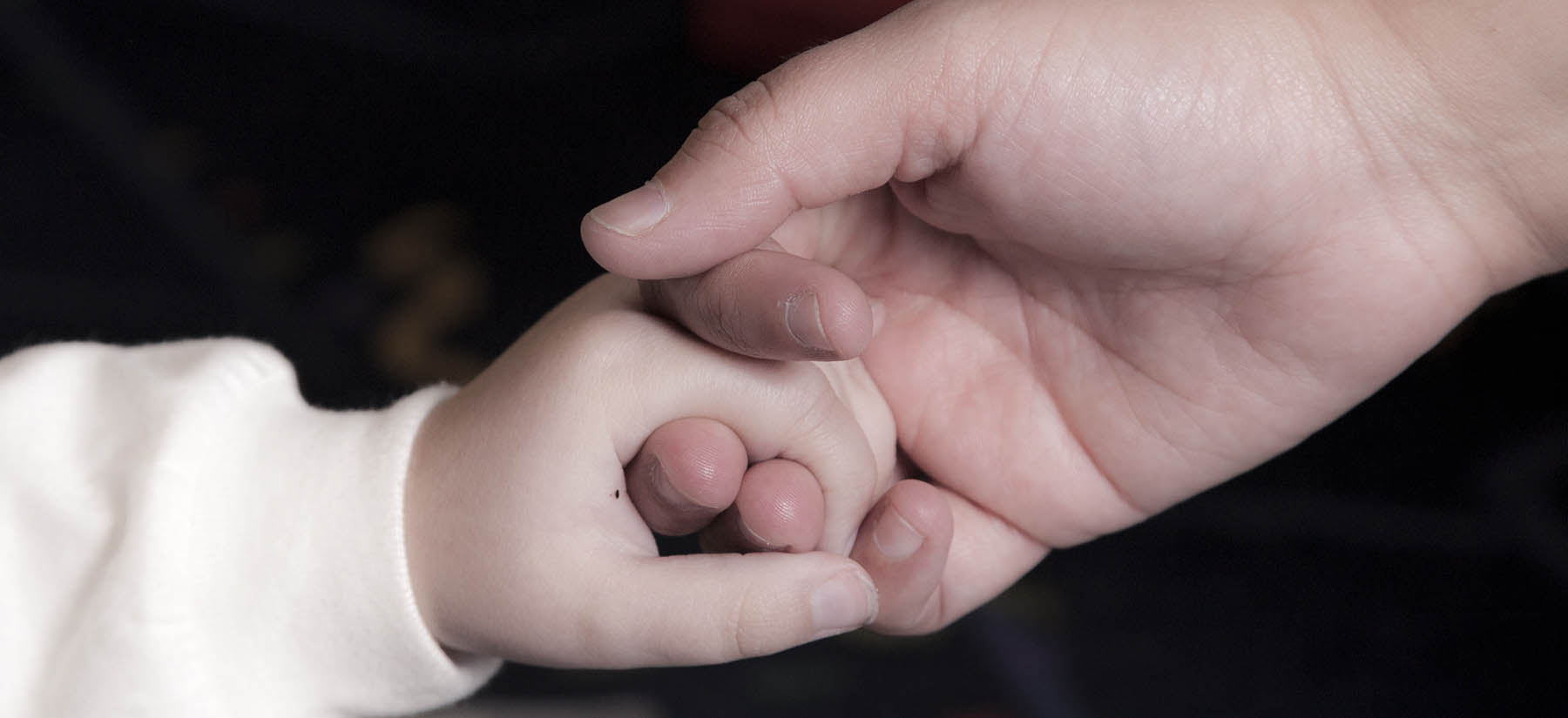 Una persona sosteniendo la mano de un niño.