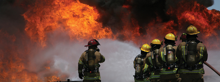 Feuerwehrleute mit einem Schlauch, um ein massives Feuer zu unterdrücken