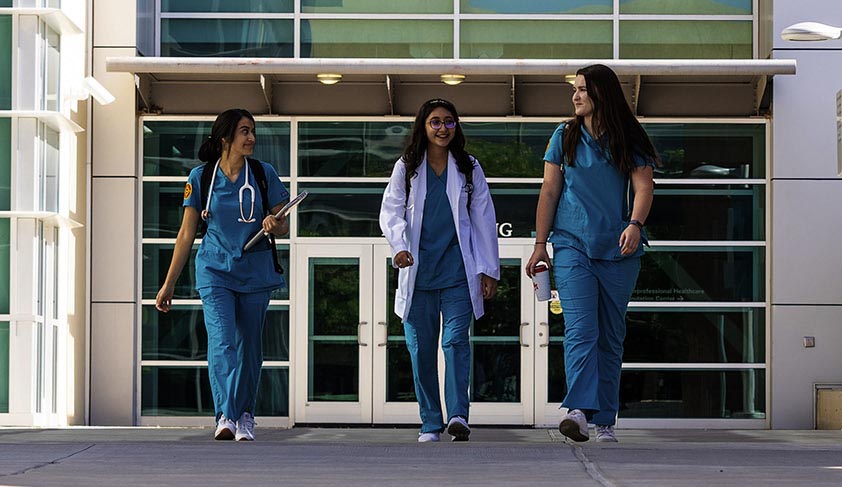 Três estudantes de enfermagem andando no campus