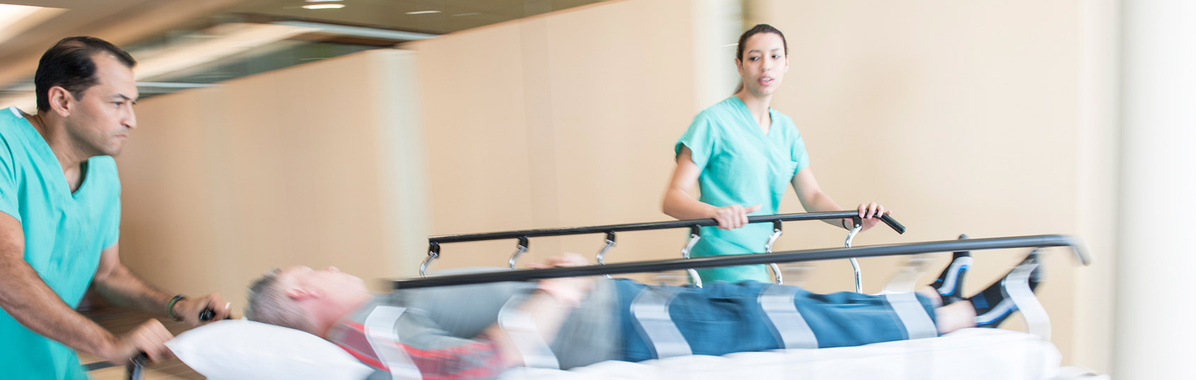 Two health professionals rushing a gurney into the ICU