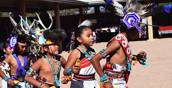 Indigenous children in ceremonial clothing performing a dance