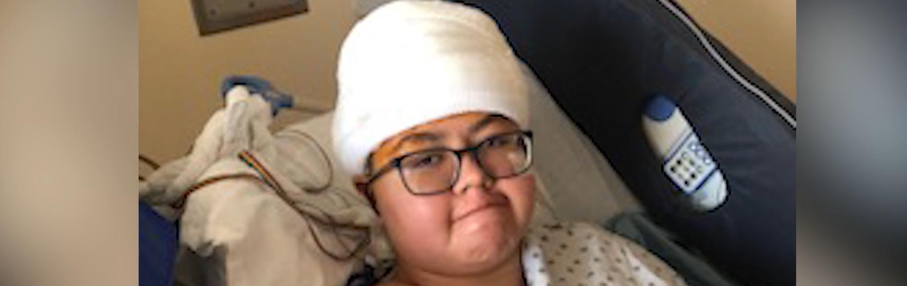 Nizhoni Begay in einem Krankenhausbett mit Verbänden auf dem Kopf
