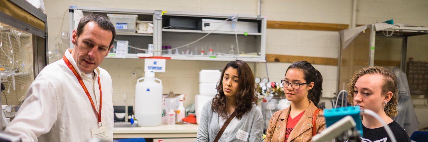 तीन हाई स्कूल के छात्रों को उपकरण दिखाते हुए एक तंत्रिका विज्ञान प्रशिक्षक
