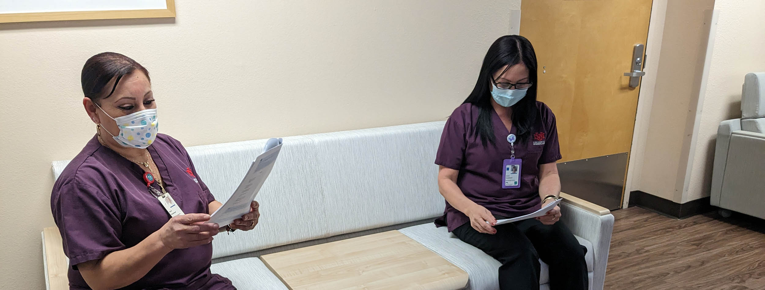 Two Critical Care Tower employees sit on a couch reading a furniture catalog
