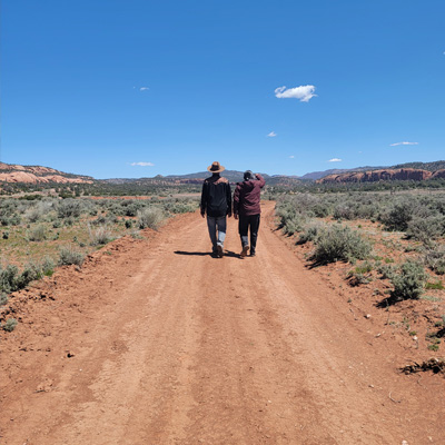 Two people walking down a dirt path.