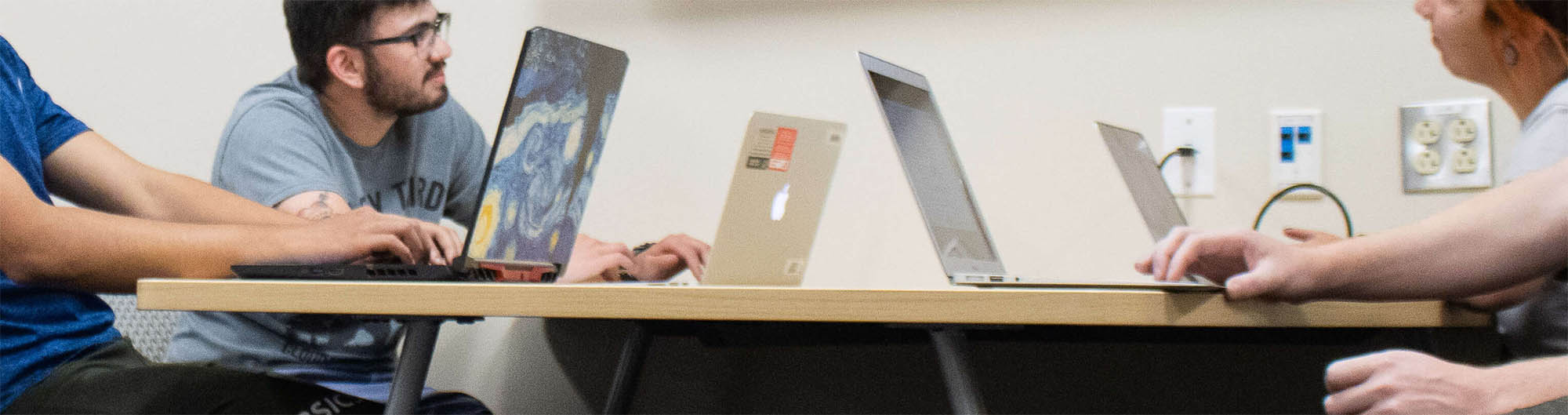 ארבעה אנשים ליד שולחן עם מחשבים ניידים