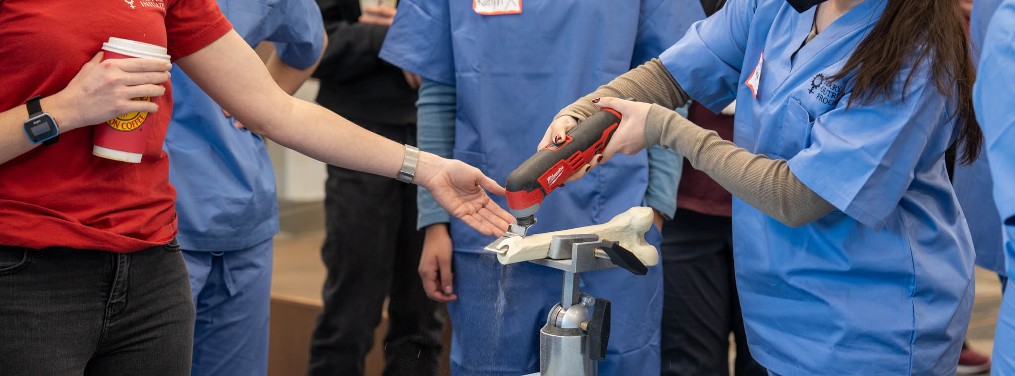 Студенты, взаимодействующие с инструментом и протезом кости