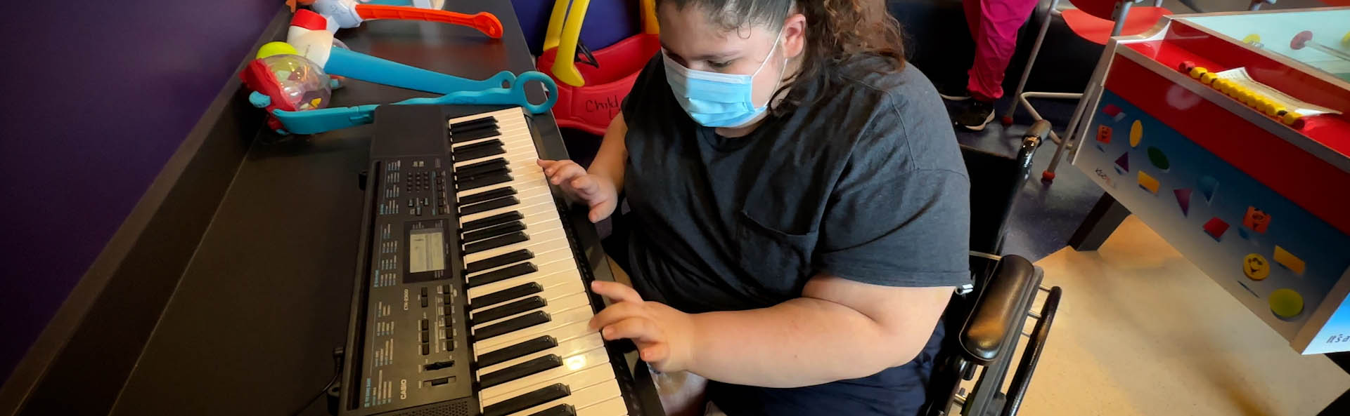 Ребенок в маске играет на клавиатуре