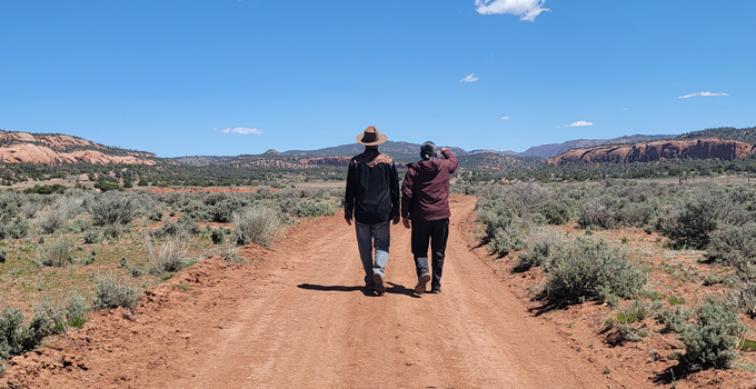 Dos personas caminando por un camino de tierra en la Nación Navajo.