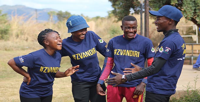 Four people wearing Zvandiri shirts and laughing