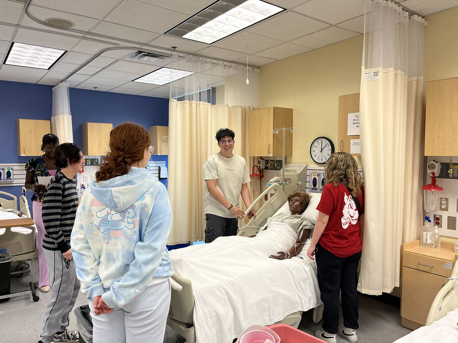 High school students attend to a dummy in a hospital bed
