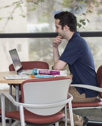 student on computer with books