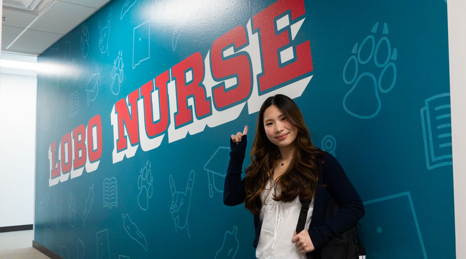 Student agains colofrul wallwrap that reads "Lobo Nurse".