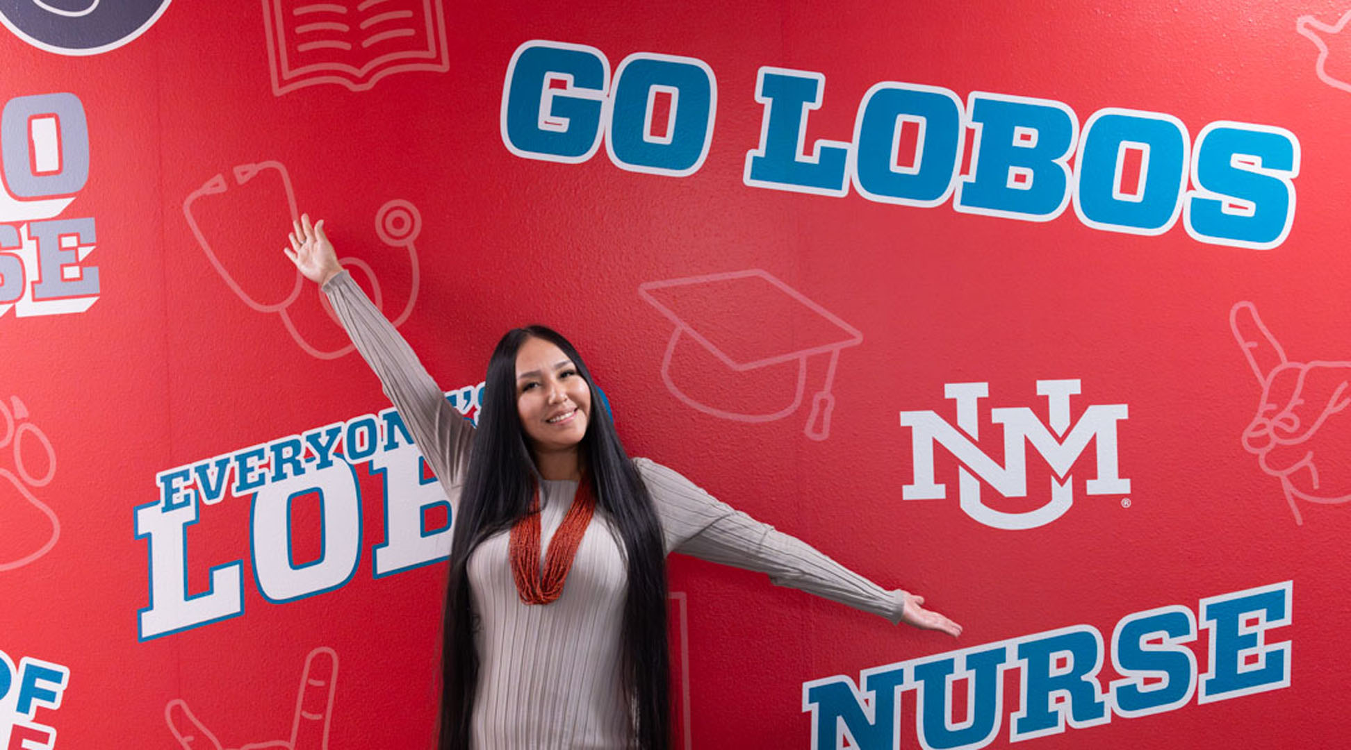Student agains colofrul wallwrap that reads "Go Lobos".