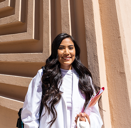 female nursing student in white coats holding books outside