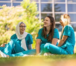 Grupo de estudantes de enfermagem sentados na grama.