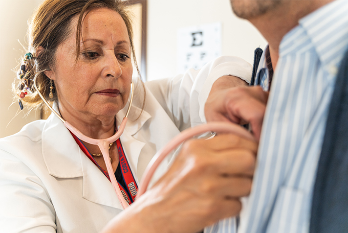 Krankenschwester, die mit dem Stethescope auf das Herz des Menschen hört.