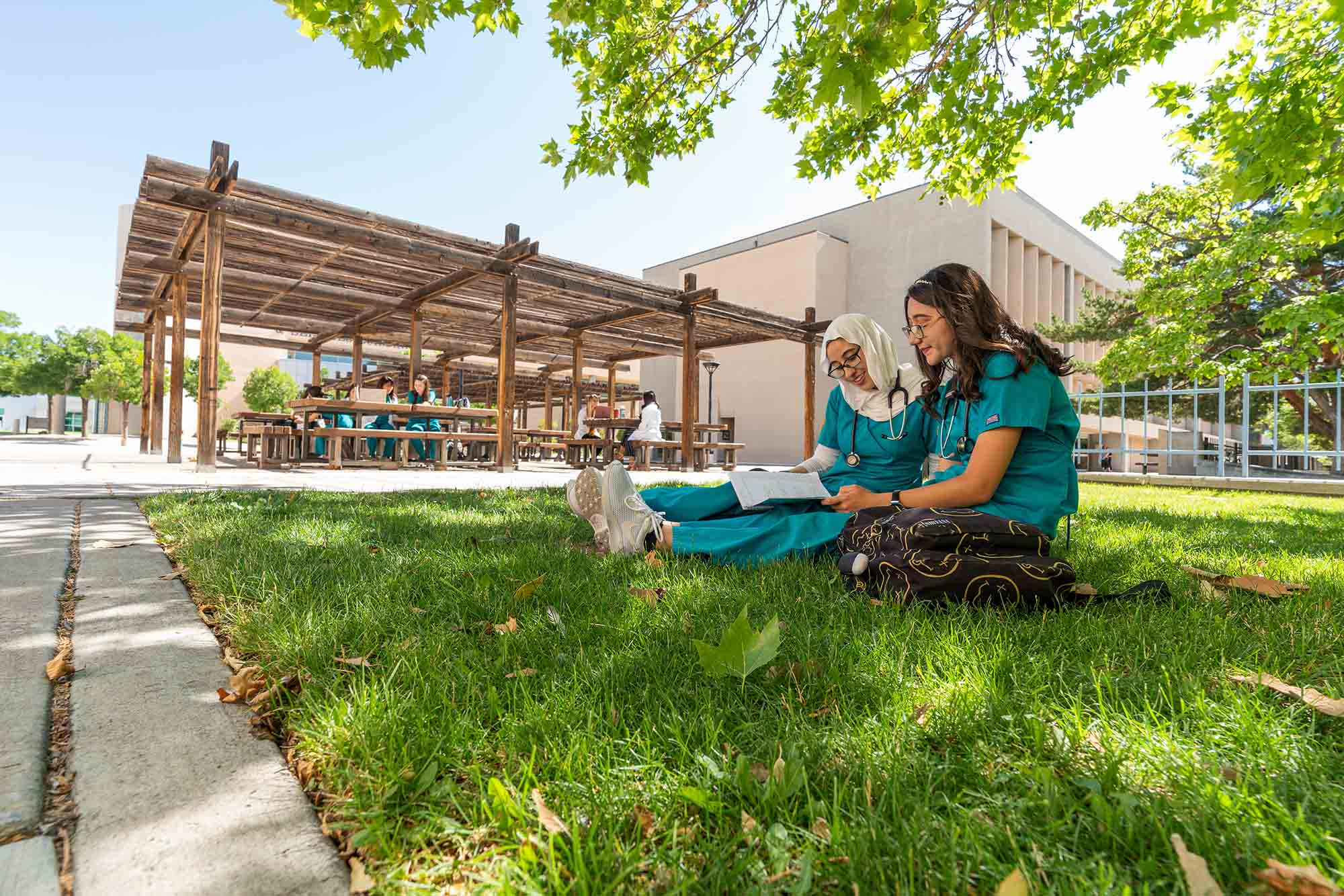 Student mit zwei Krankenpflegern, der auf Gras studiert.