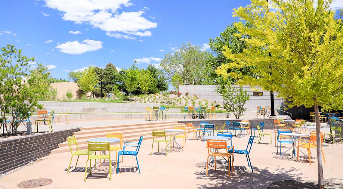Colorful chairs and tables on cement plaza.