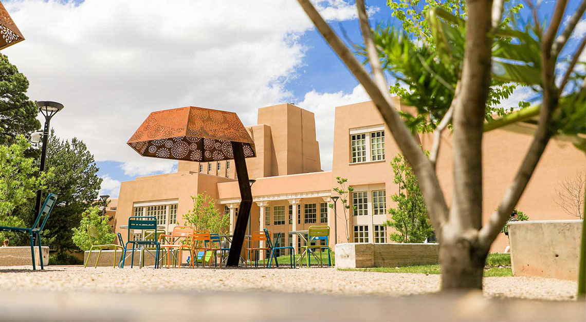 Colorful tables and chairs on plaza in front of library.