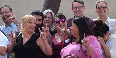 UNM HSC employees making the wolf hand sign