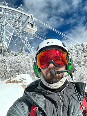 Kopfschuss eines Mannes auf einem Berg vor einem Skilift.