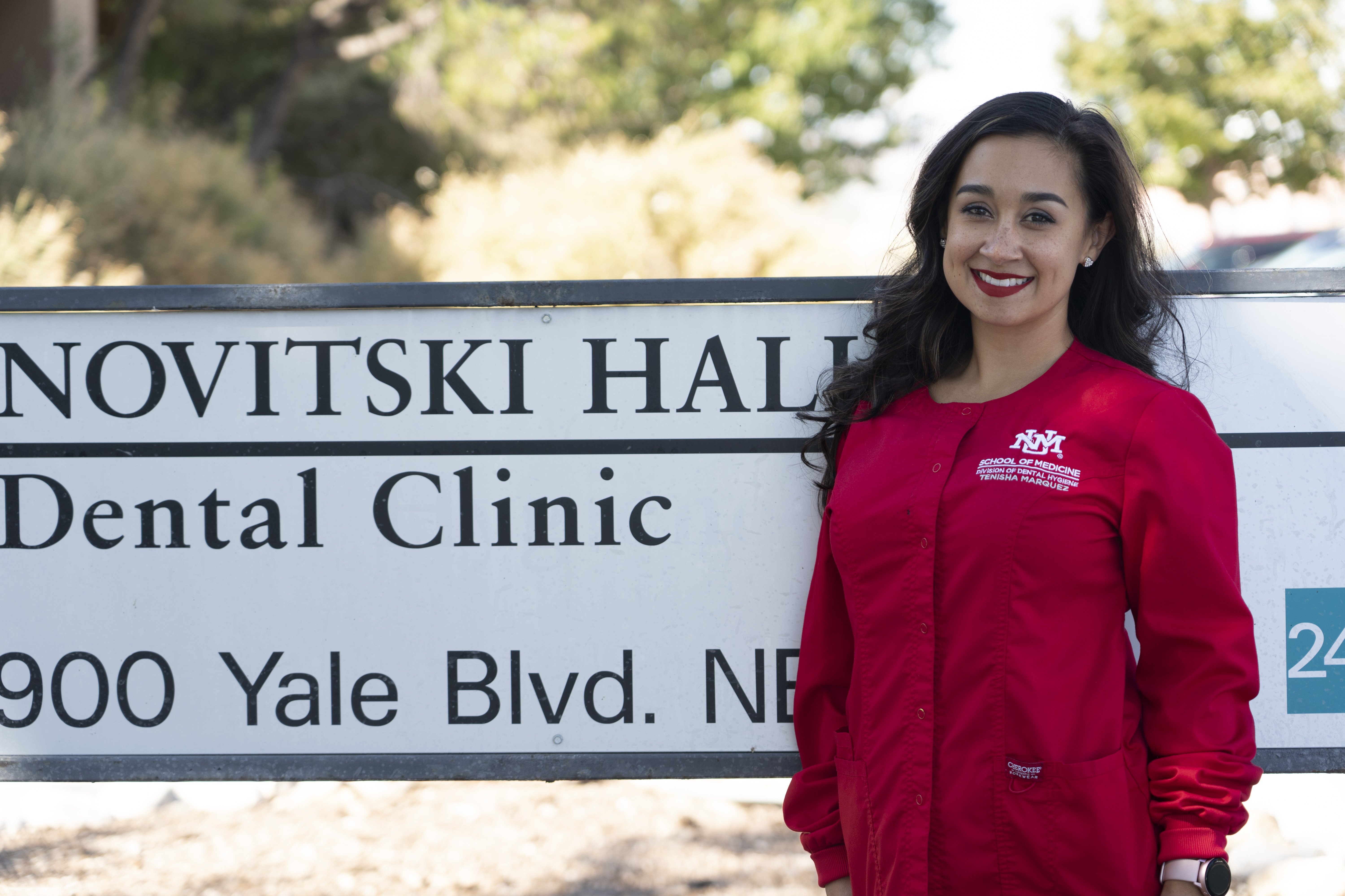 Tenisha Marquez poses by the UNM Dental Medicine building sign (Novitski Hall)